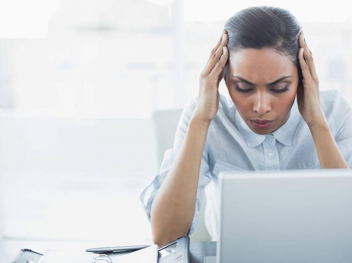 woman with hands to her head looking at laptop